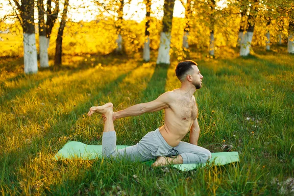 Mann praktiziert Yoga in einem Park bei schönem Sonnenuntergang. Gesunder Lebensstil — Stockfoto