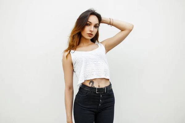 흰색 티셔츠에 아름 다운 젊은 날씬한 여자는 흰 벽 근처에 서 — 스톡 사진