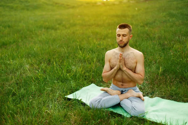 Man doing yoga in the park on nature. Meditation — Stock Photo, Image