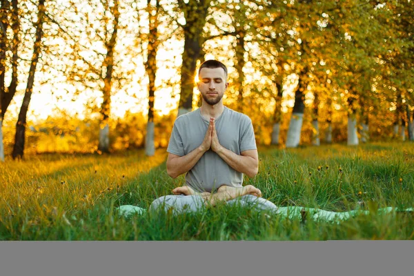 Man with a beard practicing yoga on nature at sunset. Healthy lifestyle — Stock Photo, Image