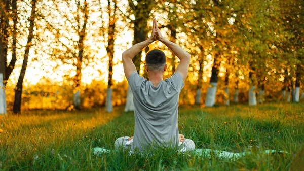 Mann meditiert Yoga praktizierend im Park bei Sonnenuntergang. Gesunder Lebensstil — Stockfoto