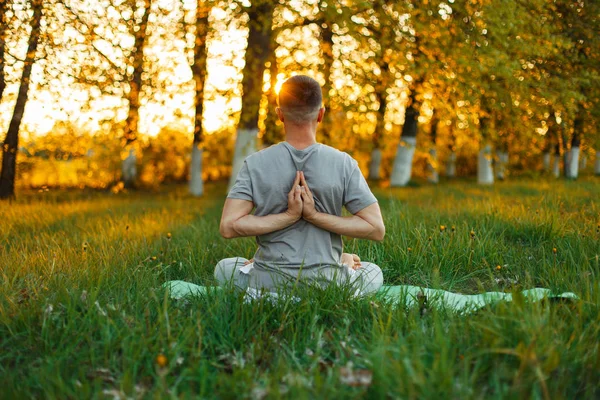 Man doing yoga in the park on a beautiful sunset. Healthy lifestyle — Stock Photo, Image