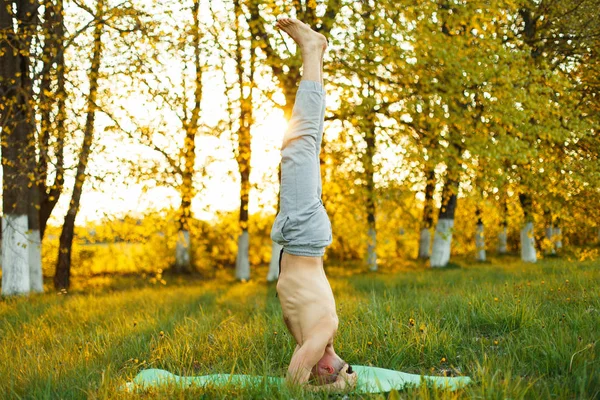 Giovanotto che fa yoga al parco al tramonto. Stile di vita sano — Foto Stock