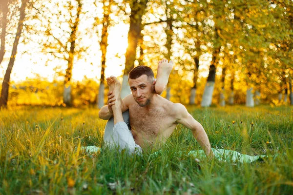 Adam kas ve parkta pratik yoga gün batımında uzanır. Sağlıklı yaşam tarzı