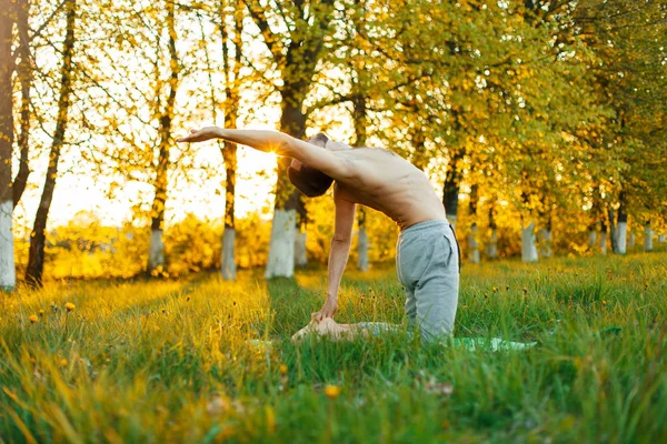 Mann praktiziert Yoga im Freien bei Sonnenuntergang. Gesunder Lebensstil — Stockfoto