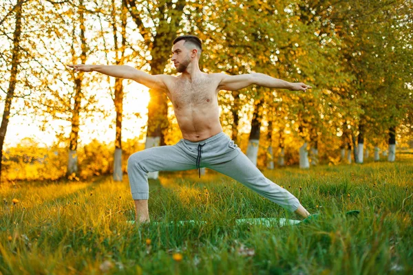 Mann praktiziert Yoga im Frühlingspark bei Sonnenuntergang. Gesunder Lebensstil — Stockfoto