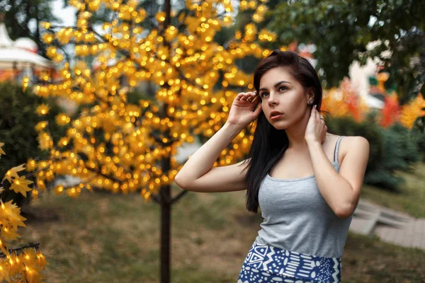 Piękna młoda kobieta w letnie ubrania w pobliżu drzewa ze światłami — Zdjęcie stockowe