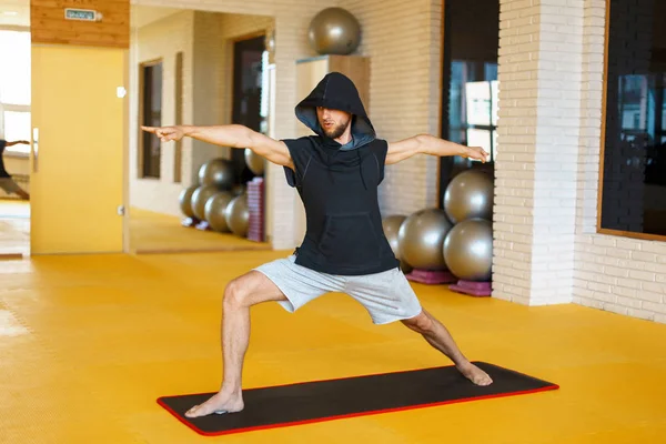 Hombre sano practicando yoga sobre un fondo amarillo en el gimnasio — Foto de Stock