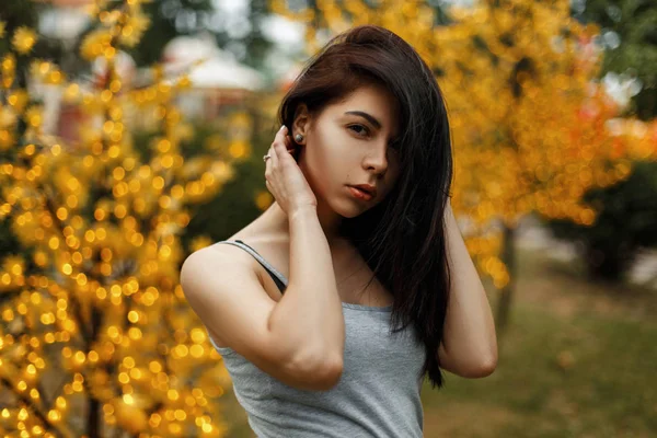 Schöne junge Frau in Sommerkleidung neben einem Baum mit Lichtern in einem Vergnügungspark — Stockfoto