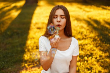 Güzel genç kadın parkta batımında sabun köpüğü ile