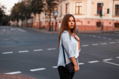 City road yakınındaki bir çanta ile mavi gömlekli casual tarzda güzel genç kız