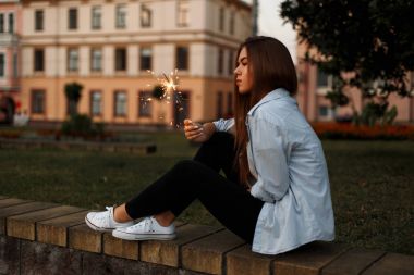 Açık havada oturma bir maytap ile rahat tarzı güzel genç kadın