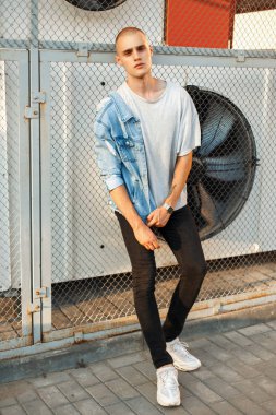 Bir kot ceket ve ızgara yakınındaki beyaz ayakkabılarla gri T-shirt Moda genç adam