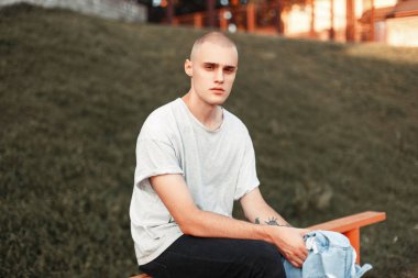 Gri bir T-shirt genç yakışıklı adam sokakta oturuyor