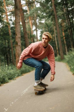 Yakışıklı genç bir pembe kazaklı bir kaykay üzerinde kaymaktadır. Sağlıklı bir yaşam tarzı kavramı