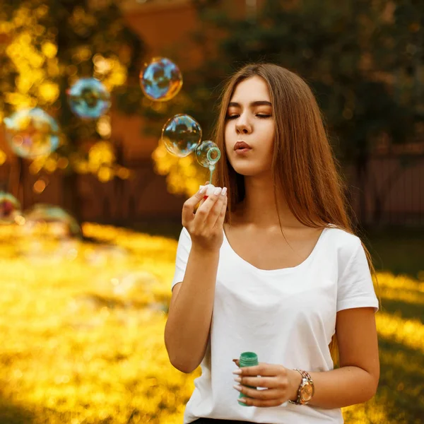 Chica joven feliz con burbujas de jabón en las vacaciones de verano al atardecer — Foto de Stock