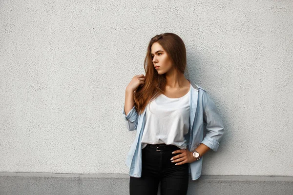 Schöne stilvolle Frau in lässigem Stil in einem blauen Hemd an der Wand — Stockfoto