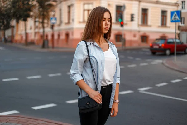 Hermosa joven mujer de moda en ropa de estilo casual de verano con bolso caminando en la ciudad — Foto de Stock