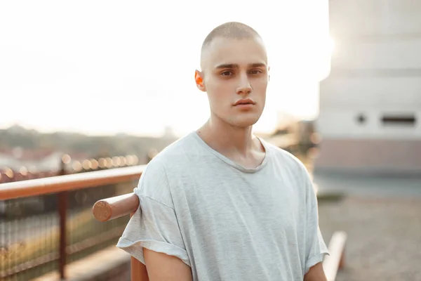 Retrato de un hermoso joven y brutal modelo hombre en una camiseta gris en la calle — Foto de Stock