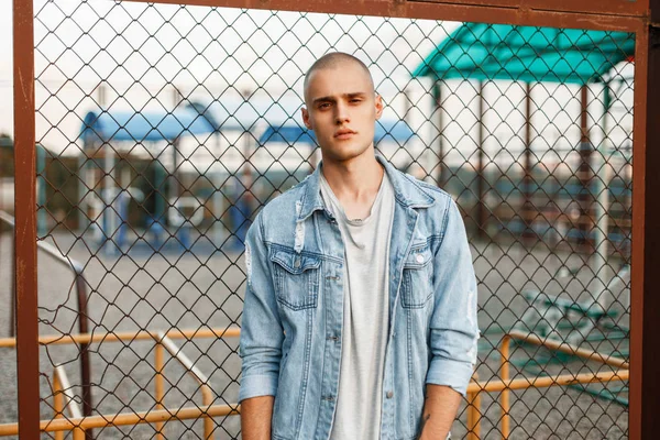 Genç adam bir kot ceket ve ızgara yakınında sokakta bir gri T-shirt