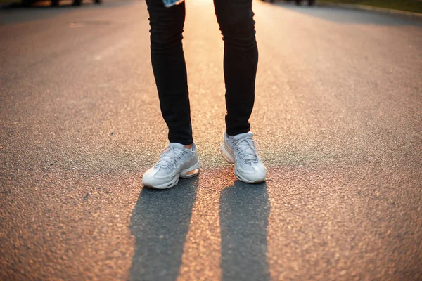 白いスニーカーと黒のパンツ夕暮れ道を男性の足 — ストック写真