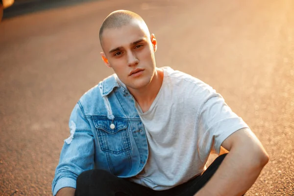 Bir kot ceket ve gün batımında yaz gri tişört ile güzel acımasız bir adam portresi