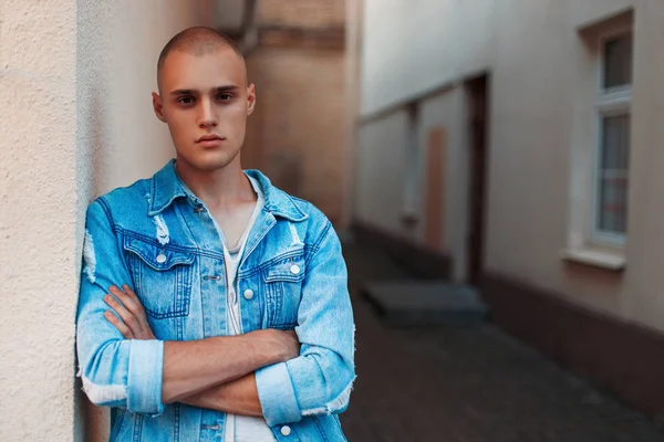 Yakışıklı genç adam sokakta bir duvarının yakınında denim kot pantolon giysili