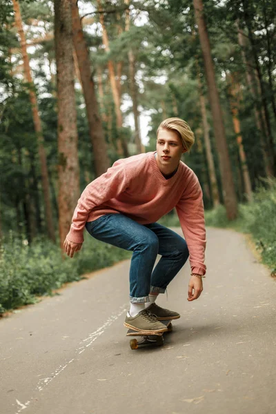 Yakışıklı genç bir pembe kazaklı bir kaykay üzerinde kaymaktadır. Sağlıklı bir yaşam tarzı kavramı