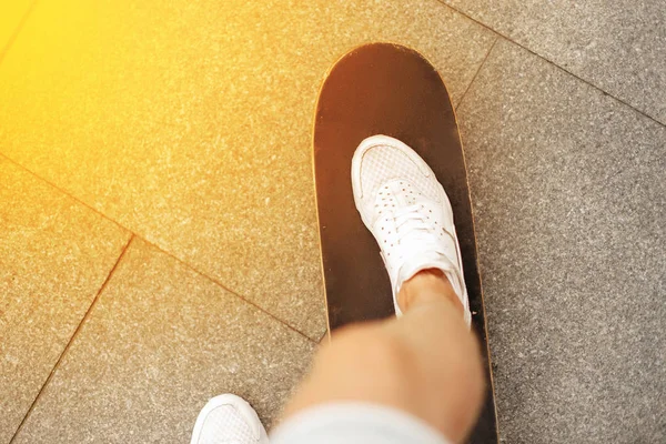 Nohy s bílé tenisky na skateboardu při západu slunce. Muž, jízda na skateboardu — Stock fotografie