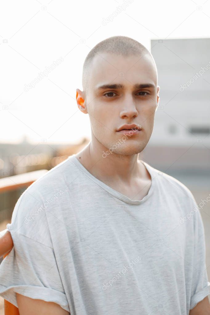 Portrait of a young brutal man in a stylish gray shirt outdoors