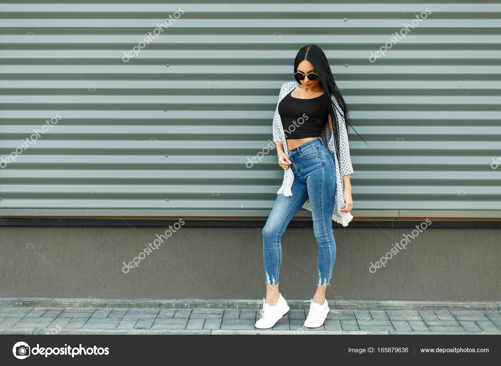 Beautiful Stylish Woman In A Fashionable White Cloak With A Black T Shirt And Blue Jeans With A High Waist With White Shoes Near The Metal Wall In The Street Stock Photo By C