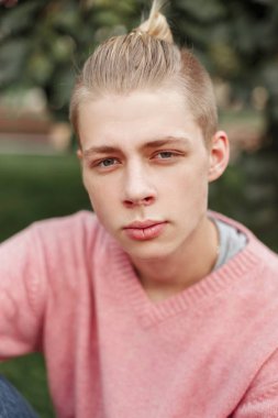 Parkta bir pembe kazaklı genç bir adam portresi