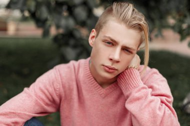 Parkta bir pembe kazaklı yakışıklı bir genç adam portresi