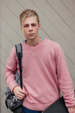 Yakışıklı genç bir sırt çantası ve plaja yakın bir ahşap duvar kaykay ile