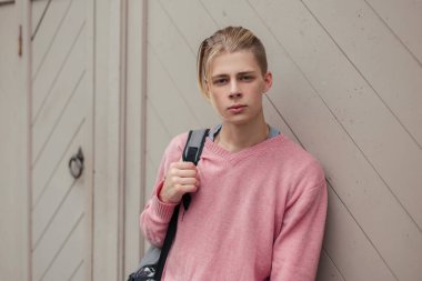 Duvarın yanında bir sırt çantası ile yakışıklı şık genç adam