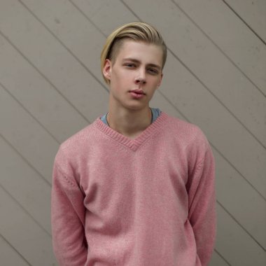 Pembe kazaklı bir ahşap duvar yakınındaki yakışıklı bir adam portresi