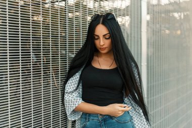 Duvara yakın poz rahat kıyafetler içinde vintage güneş gözlüğü ile uzun saçlı güzel kadın moda