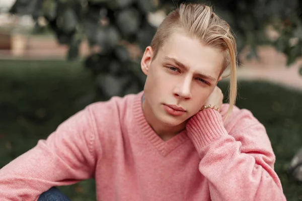 Πορτρέτο του ένας όμορφος νεαρός άνδρας σε ένα ροζ πουλόβερ στο πάρκο — Φωτογραφία Αρχείου