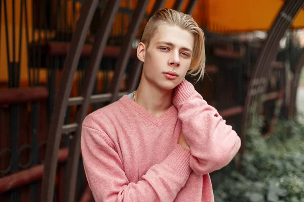 Stilig ung modell man med en blond frisyr i en rosa tröja på gatan — Stockfoto