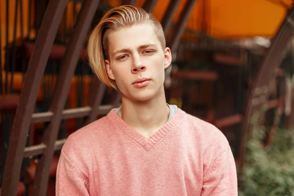 Όμορφος μοντέρνος νέος σε ένα ροζ πουλόβερ στο πάρκο — Φωτογραφία Αρχείου