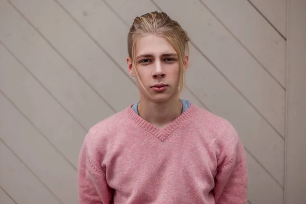 Beau jeune modèle masculin en pull rose près d'un mur en bois — Photo