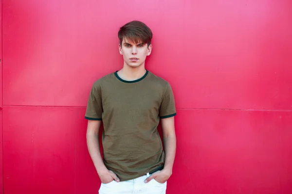 Hombre guapo de moda en una camiseta verde cerca de una pared de metal rosa — Foto de Stock