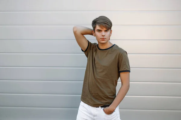 Jovem bonito em uma camiseta de moda perto da parede cinza — Fotografia de Stock