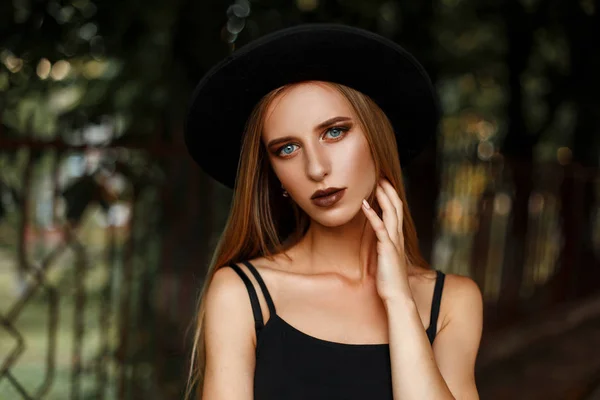 Hermosa mujer con maquillaje en un sombrero negro de moda en el parque — Foto de Stock