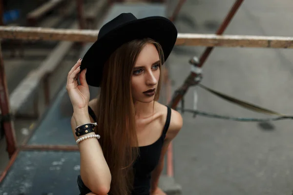 Egy gyönyörű fiatal nő, egy fekete divatos kalap szabadban portréja — Stock Fotó