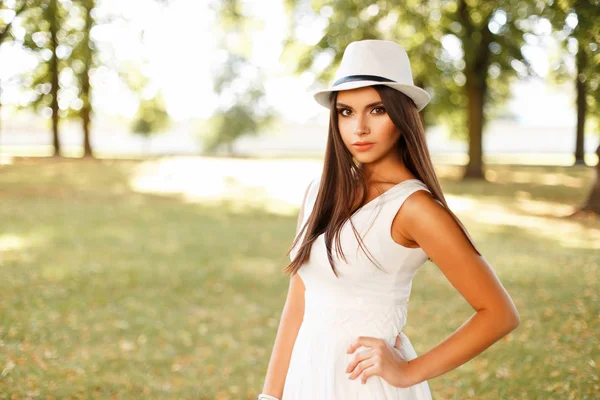 Piękna młoda kobieta w białych strojach z kapelusz pozowanie na zewnątrz w letni dzień — Zdjęcie stockowe