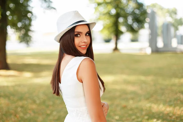 Szczęśliwa młoda kobieta z uśmiechem w białej sukni z czapką w letni dzień na świeżym powietrzu — Zdjęcie stockowe