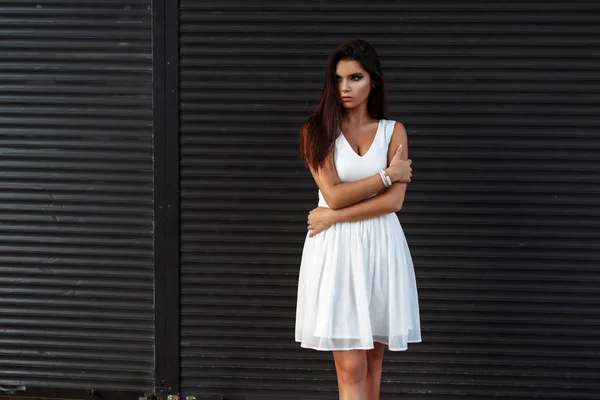 Bella donna alla moda in un vestito bianco vicino a rotoli di metallo — Foto Stock