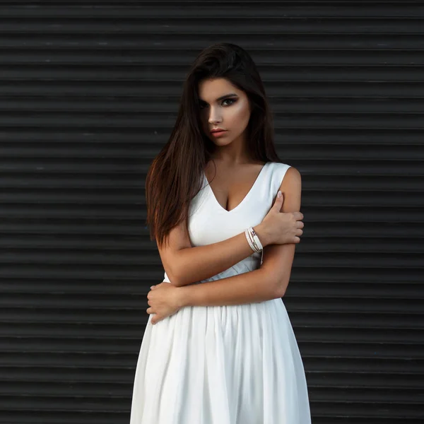 Mulher bonita com maquiagem em vestido branco perto de metal parede escura — Fotografia de Stock