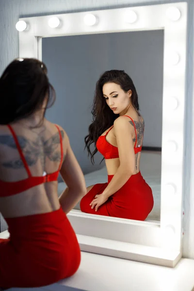 Belle femme sexy dans un soutien-gorge rouge et jupe rouge près d'un miroir vintage dans la chambre — Photo